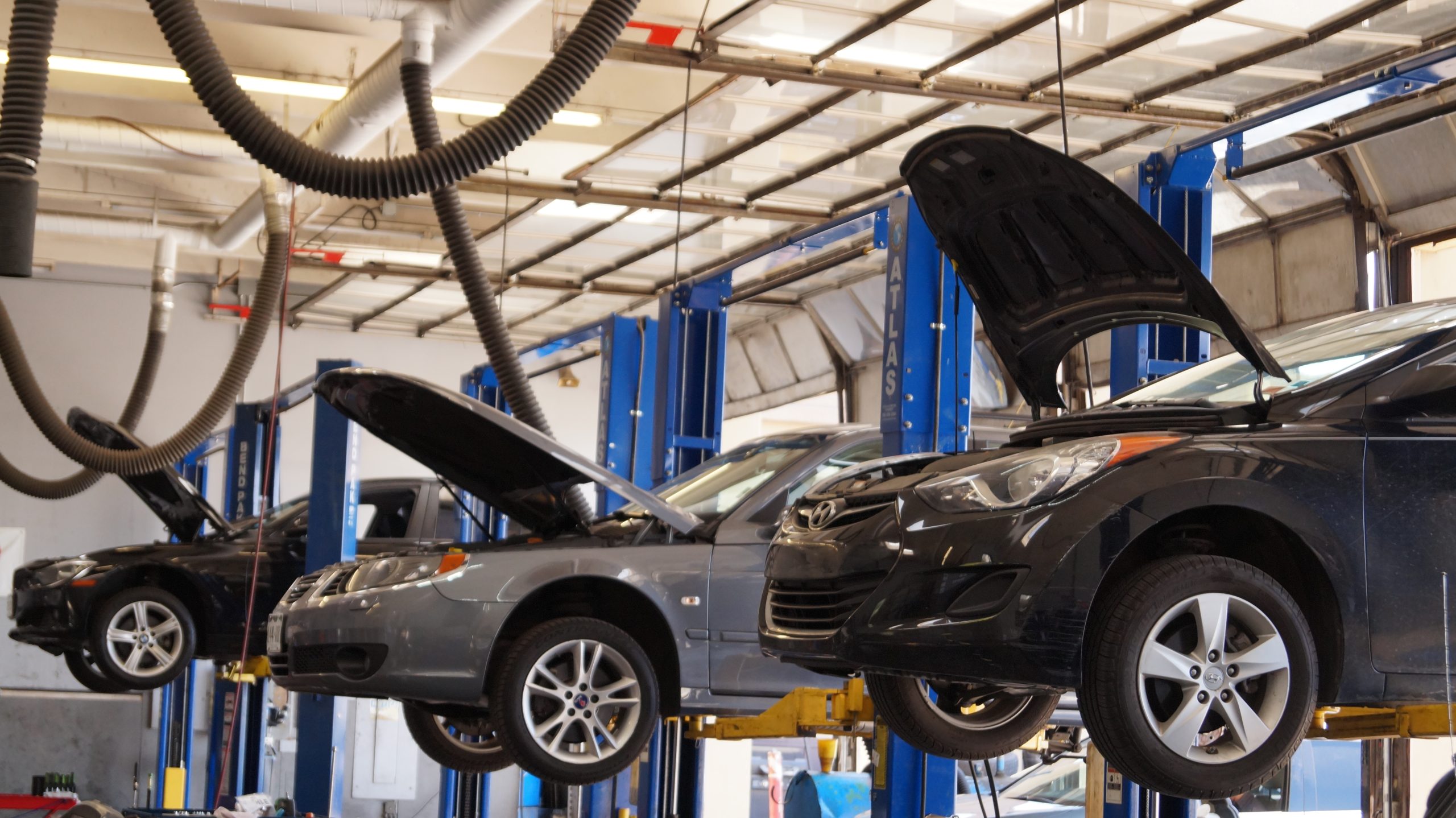 Cars with open hoods on lifts inside the Community Auto Repair service bay